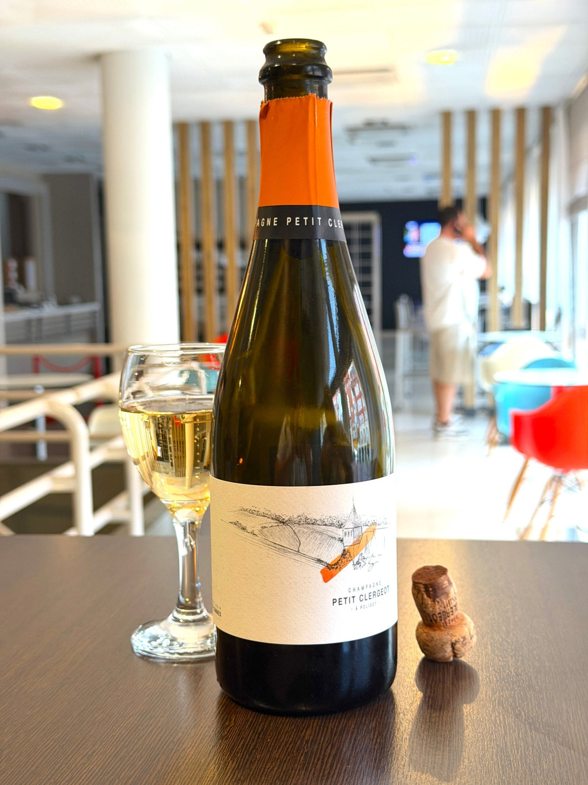 Bottle of Champagne Petit Clergeot a Polisot with a poured glass and the cork beside it