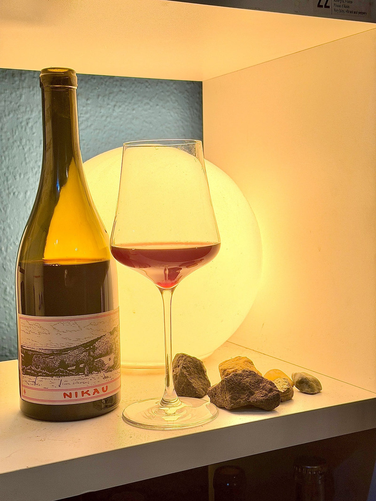 Bottle of Nikau from Gippsland with a glass of pale red wine and volcanic stones